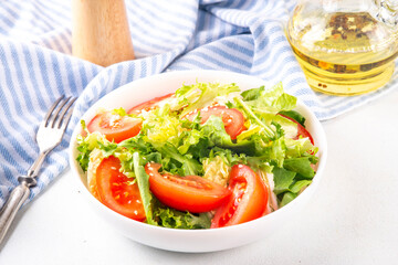 Simple minimal healthy vegetable salad with lettuce, sliced tomatoes, sesame seeds and olive oil 