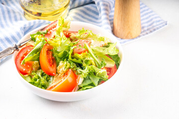 Simple minimal healthy vegetable salad with lettuce, sliced tomatoes, sesame seeds and olive oil 