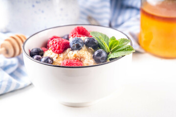 Breakfast oatmeal with fresh berries and honey/ Portioned breakfast oats with raspberry, blueberry and honey, healthy balanced morning food