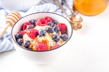 Breakfast oatmeal with fresh berries and honey/ Portioned breakfast oats with raspberry, blueberry and honey, healthy balanced morning food