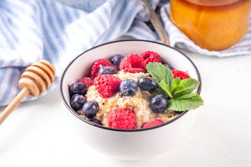 Breakfast oatmeal with fresh berries and honey/ Portioned breakfast oats with raspberry, blueberry and honey, healthy balanced morning food