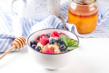 Breakfast oatmeal with fresh berries and honey/ Portioned breakfast oats with raspberry, blueberry and honey, healthy balanced morning food