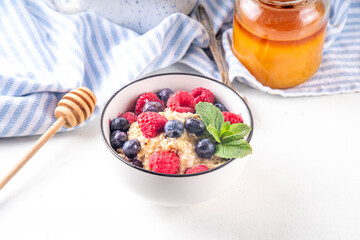 Breakfast oatmeal with fresh berries and honey/ Portioned breakfast oats with raspberry, blueberry and honey, healthy balanced morning food