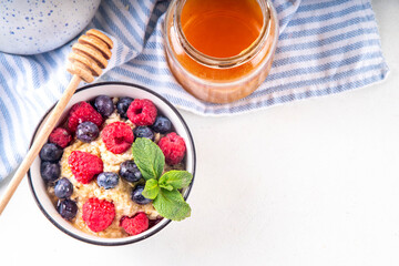 Breakfast oatmeal with fresh berries and honey/ Portioned breakfast oats with raspberry, blueberry and honey, healthy balanced morning food