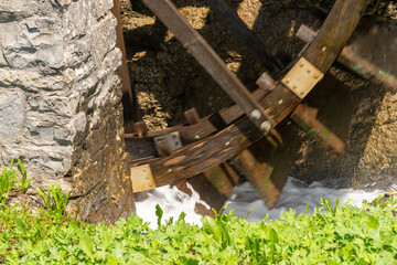 Closeup of old mill wheel at a river. Shadows on the building walls. The rotation of the wooden...