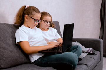 Children playing on a laptop at home. A concept of digital entertainment and learning in a comfortable home setting.