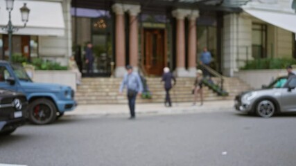 Blurred pedestrians and luxury cars in front of a grand hotel entrance on a street in monaco capture the essence of elegance and opulence.