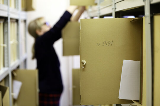 Document archive, defocused view to archivist woman with papers in the storage