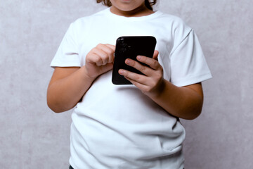 A teenager using a mobile phone on a light background. A concept of modern technology and communication.