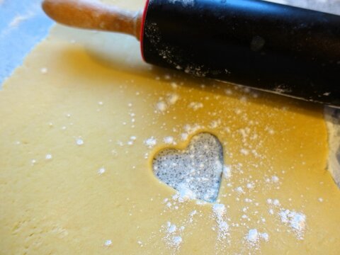Heart-shaped cutout in dough with rolling pin.
