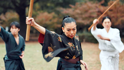 Martial arts, Japanese people and instructor with wood sword for fight, battle and samurai training class. Park, ninja and mentor with weapon, kendo and warrior in autumn in Japan with fighter group © peopleimages.com