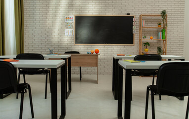 Empty school astronomy classroom with desks, chairs and chalkboard at daylight, workspace for learning and teaching. Tables with planet models, full shot.