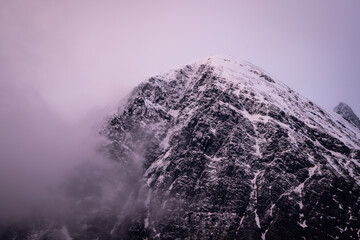 Fog covered mountain peak at purple sunset 