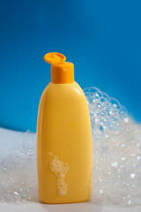 A vibrant yellow shampoo bottle stands out, encircled by soft bubbles, all set against a striking blue backdrop