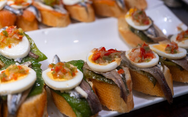 Typical snack of Basque Country, pinchos or pinxtos skewers with small pieces of bread, sea food, eggs, cheese, jamon served in bar in San-Sebastian or Bilbao, Spain, close up