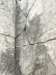 Deep cracks in marble floor, close-up. Damaged marble, old surface. Signs of deterioration of wall or floor covering in a building.