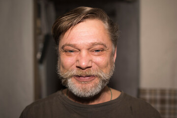 Fototapeta premium A man with facial hair, including a beard and moustache, is smiling for the camera at an event. His wrinkled nose and jawline show he is pleased, wearing a tshirt