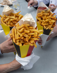 Belgian street and fast food, paper cone bag in colors of Belgian flag with fried potato frit chips...