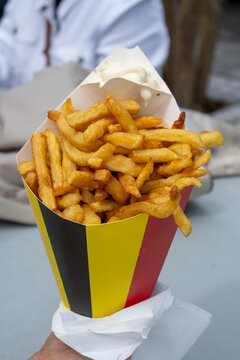 Belgian street and fast food, paper cone bag in colors of Belgian flag with fried potato frit chips and mayonnaise sauсe.