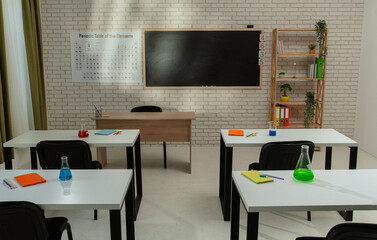 Empty school chemistry classroom with desks, chairs and chalkboard, workspace for teaching and studying. Glass bottles with liquids on tables, above view.