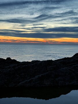 Dusk sky clouds over calm ocean and coast 