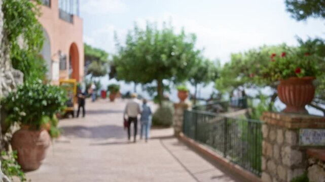 Blurred couple strolling through charming capri street lined with lush greenery, showcasing italian island luxury and tranquility.