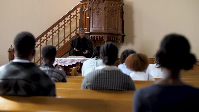 Congregation listening to priest giving sermon in church