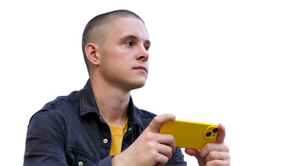 A young man with a short haircut holds a yellow smartphone. He sits lost in his thoughts and engaged in an online activity, enjoying a calm moment.
