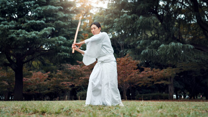 Nature, martial arts and Asian woman with bamboo sword in park for training, Kendo practice and exercise. Culture, bokuto and person with shinai for skills, fitness and traditional sports in Japan