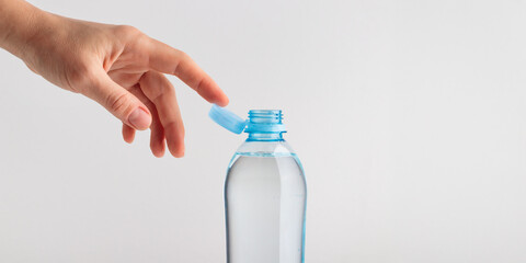 Stationary plastic cap on a PET bottle with human's hand. The new design means the cap remains...