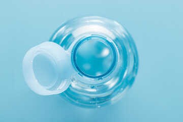 Close up of new cap attached to plastic bottle, connected to the neck of the bottle by solid tab...
