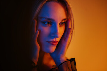 Close-up of a woman with hands on her face, blue and orange lighting