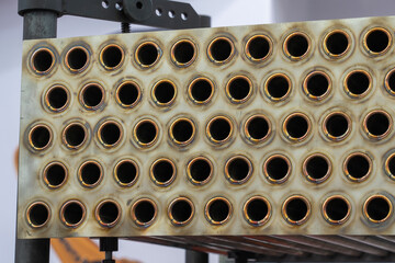 Rows of circular openings are arranged in a metallic panel at a workshop, highlighting interesting...
