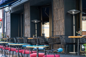 Stylish outdoor seating features black wicker chairs and colorful tables, inviting guests to enjoy their meals in a lively atmosphere under clear skies