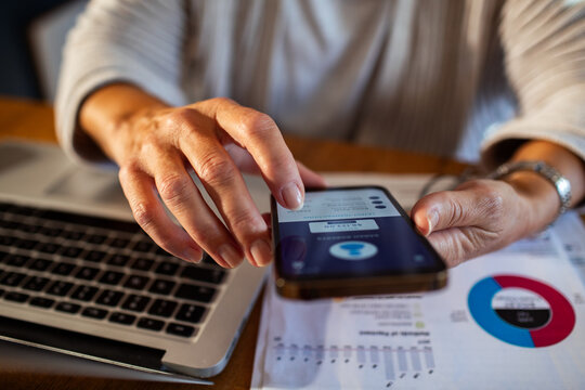 Close up of woman hands using smartphone for online banking at home