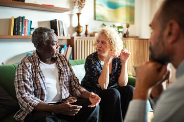 Senior couple having a serious conversation with financial advisor in living room