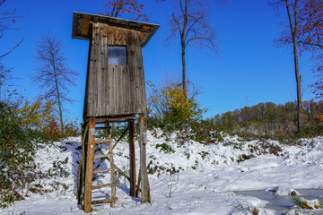 A high wooden hunter's stand at the edge of the forest, overlooking a large forest
