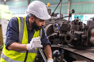 Male factory worker working with heavy machinery in industrial factory