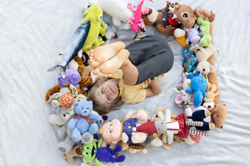 barefoot boy raised his feet up. There are many different colorful soft toys laid out around him. play at home with toys . develop imagination, interesting childhood, imaginary friends. Top view