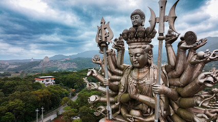 Holy Thousand Hand Guanyin statue overlooks lush landscape in Taiwan under overcast sky