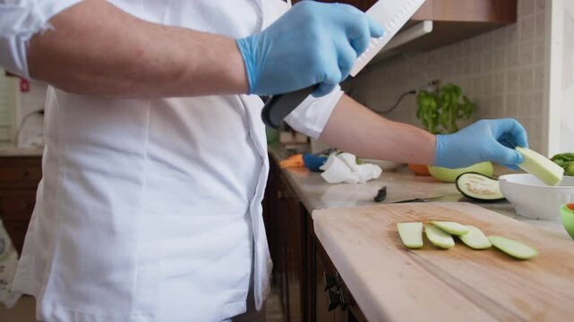 Chef Cuts Zucchini Vegetable On A Wooden Cutting Board In Restaurant Kitchen