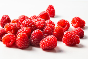 Ripe raspberries in a white bowl, on a red napkin. Raspberry cultivation and use.