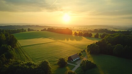 Naklejka premium Aerial view of sunrise over rural landscape with farmhouse.