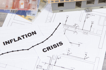 Inscriptions crisis and inflation, currencies Euro, small house under construction on electrical installation plan. High prices of real estate, building or rent home
