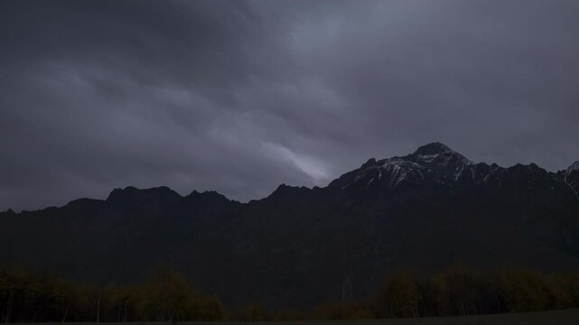 Timelapse of mountain range with moving clouds in sky.