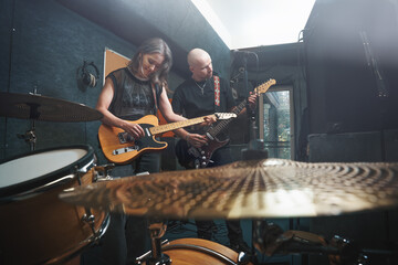 Musicians practicing in music studio with electric guitars and drum set, creating vibrant atmosphere of live performance. Captures teamwork, creativity, passion for music