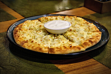 Megruli khachapuri with a cup of sour cream in the middle.