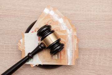 top view of Judge's Gavel on a Pile of Euro Banknotes on wooden background, financial judgment or...