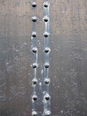 Heavy steel rivets on a sheet of steel painted black