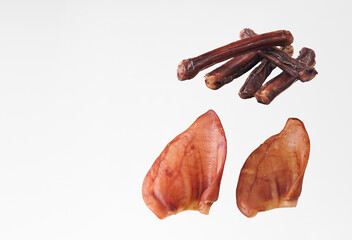 A natural chewy treat for dogs on a white background. Useful treats for pets of all breeds and ages "bull penis" and dried pig ears. Photo with copy space